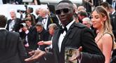 Influencer Italia Khaby Lame tiba untuk pemutaran film "Top Gun : Maverick" selama Festival Film Cannes edisi ke-75 di Cannes, Prancis selatan (18/5/2022). Khaby tampil dengan setelan jas dan kaca mata hitam. (AFP/Christophe Simon)