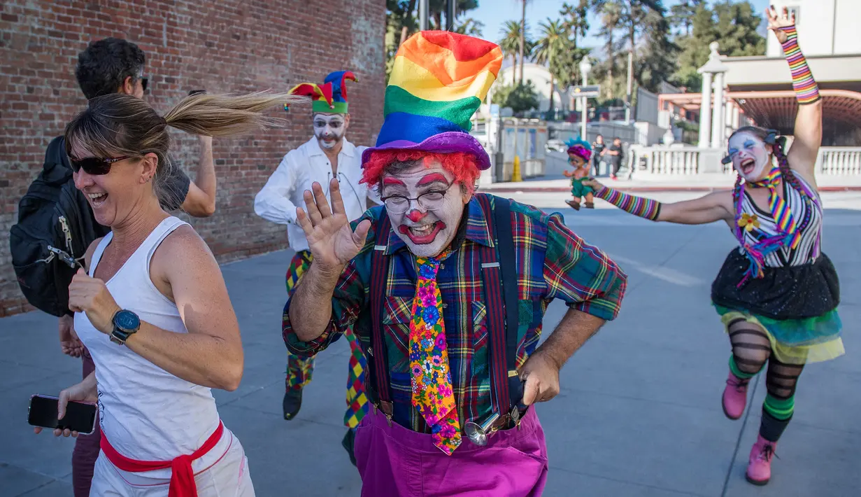 Para peserta berdandan seperti badut berlarian selama acara parodi tahunan "Running of the Clowns" di Pasadena, California pada 20 Oktober 2019. Lari dikejar kawanan badut ini merupakan parodi yang mengolok-olok lomba dikejar banteng di Spanyol. (Mark RALSTON / AFP)