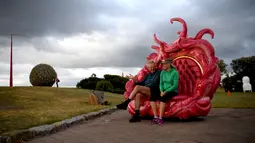 Pengunjung duduk di salah satu karya patung yang dipamerkan di pantai Bondi hingga Tamarama di Sydney, Rabu (19/10). Pameran yang bernama ‘Sculpture by the sea’ merupakan pameran patung tahunan diluar ruangan yang terbesar di Australia. (PETER PARKS/AFP)