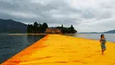 Seorang wanita berjalan diatas instalasi seni 'The Floating Piers' buatan seniman kelahiran Bulgaria Christo Vladimirov Yavachev atau dikenal sebagai Christo , di Danau Iseo , Italia utara , (16/6). (REUTERS / Stefano Rellandini)