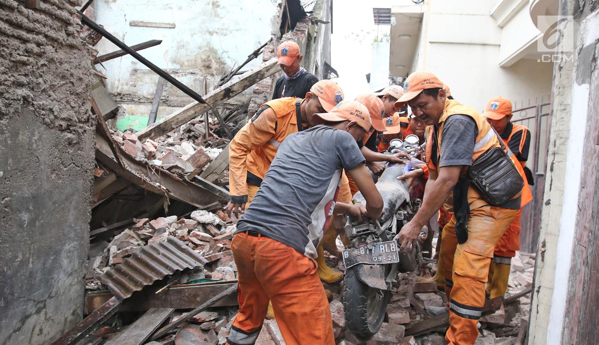 Petugas PPSU mengevakuasi sepeda motor yang tertimpa bangunan SMPN 32 Pekojan Jakarta Barat yang roboh pada Kamis (21/12). Diduga bangunan ini roboh karena usia yang sudah terlalu tua. (Liputan6.com/Herman Zakharia)