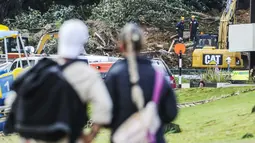Operasi pencarian dan penyelamatan masih berlangsung di lokasi perkemahan Gunung Maunganui yang merupakan salah satu destinasi populer di pantai utara Selandia Baru. Tampak dalam foto, sepasang suami istri melihat tanah longsor sementara pencarian sedang dilakukan oleh layanan darurat setempat untuk orang hilang di Gunung Maunganui, Tauranga, Selandia Baru pada Kamis 22 Januari 2026. (DJ MILLS/AFP)