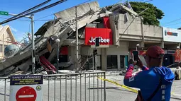 Warga mengambil foto bangunan yang runtuh akibat gempa bumi di General Santos, Filipina, Senin 8 Juni 2026. (AP Photo)