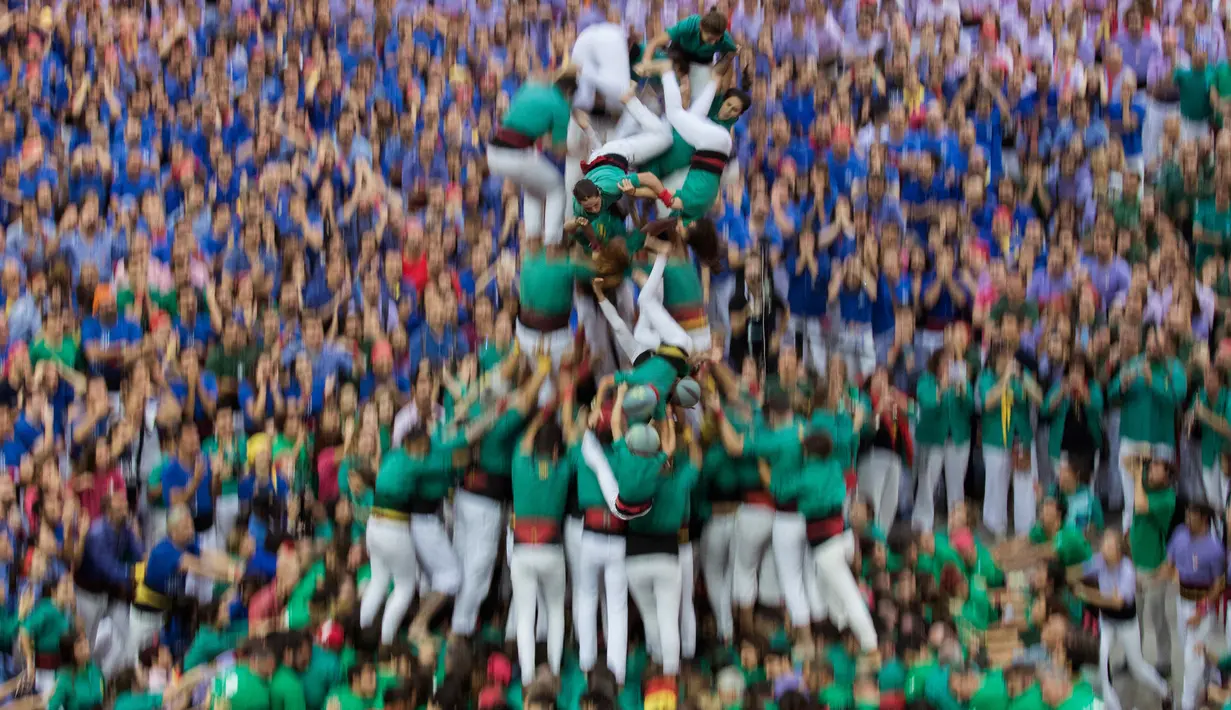 Anggota "Castellers de Sabadell" terjatuh saat membentuk menara manusia selama Kompetisi Tower Manusia di Tarragona, Spanyol, Minggu (7/10). Proses membuat menara manusia ini menjadi hal yang paling menarik untuk ditonton. (AP/Emilio Morenatti)