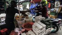 Penjual tempe melayani pembeli di Pasar Kebayoran Lama, Jakarta, Selasa (15/2/2022). Tempe dan tahu akan hilang di pasar tradisional dikarenakan kenaikan harga kedelai saat ini sudah di atas kewajaran. (Liputan6.com/Johan Tallo)