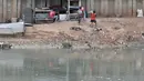 Anak-anak bermain di pinggir aliran Kanal Banjir Barat yang tengah dipenuhi sampah, Jakarta, Senin (22/10). Sampah yang memenuhi aliran kanal pencegah banjir tersebut didominasi plastik dan limbah rumah tangga. (Merdeka.com/Iqbal Nugroho)