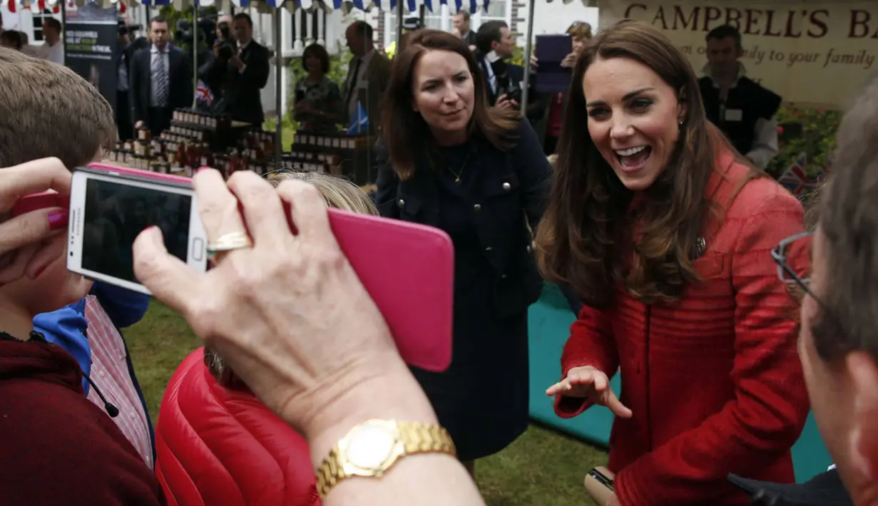 Salah satu warga Forteviot, Skotlandia terlihat mengabadikan kedatangan Duchess of Cambridge, Catherine Elizabeth Middleton dengan kamera ponsel, (29/5/2014). (REUTERS/Russell Cheyne)