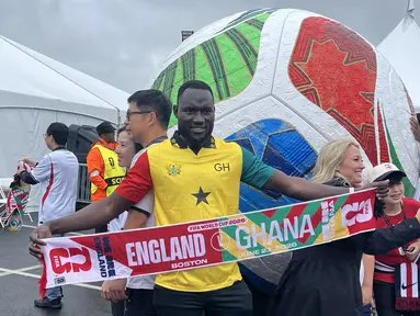 Seorang suporter Ghana membentangkan syal saat berpose di depan instalasi bola raksasa Piala Dunia 2026 di area Gillette Stadium, Foxborough, Boston, AS, Senin (23/6/2026). Antusiasme suporter kedua tim mewarnai laga fase grup Piala Dunia 2026 antara Inggris dan Ghana. (KLY Sports/Hery Kurniawan)