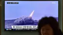 Seorang wanita melewati layar yang menyiarkan berita tentang peluncuran roket Korut, di stasiun kereta di Seoul, Korsel, Jumat (4/3). Kim Jong-Un memerintahkan pasukannya menyiagakan senjata nuklir untuk bisa digunakan kapan saja. (AFP PHOTO/Jung YEON-JE)