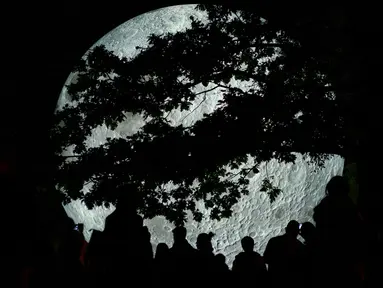 Sejumlah pengunjung melihat karya seni replika bulan raksasa yang dipajang di Bratislava, Slovakia, 7 Oktober 2017. Replika bulan tersebut merupakan karya seniman Inggris, Luke Jerram yang bertajuk 'Museum of The Moon'. (JOE KLAMAR / AFP PHOTO)