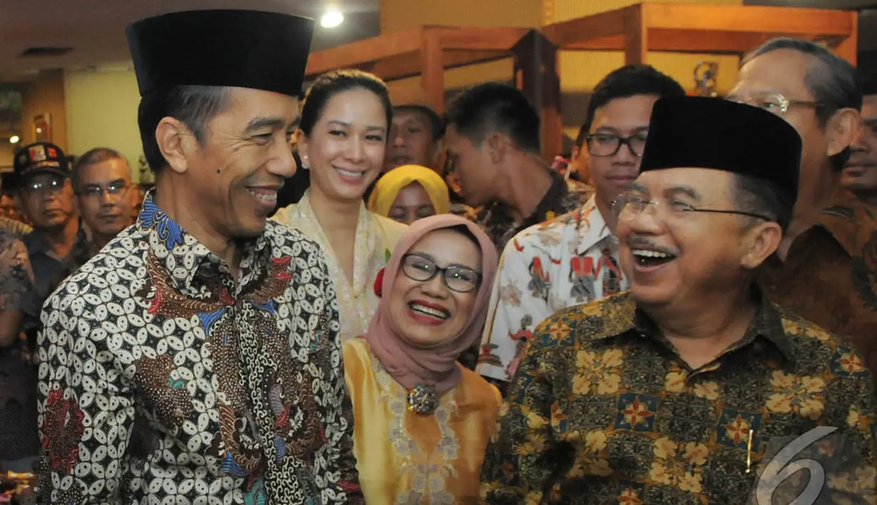 Jokowi dan JK tersenyum satu sama lain setelah memakai kopiah, Pasaraya Blok M, Jakarta, Kamis (2/10/2014) (Liputan6.com/Herman Zakharia)