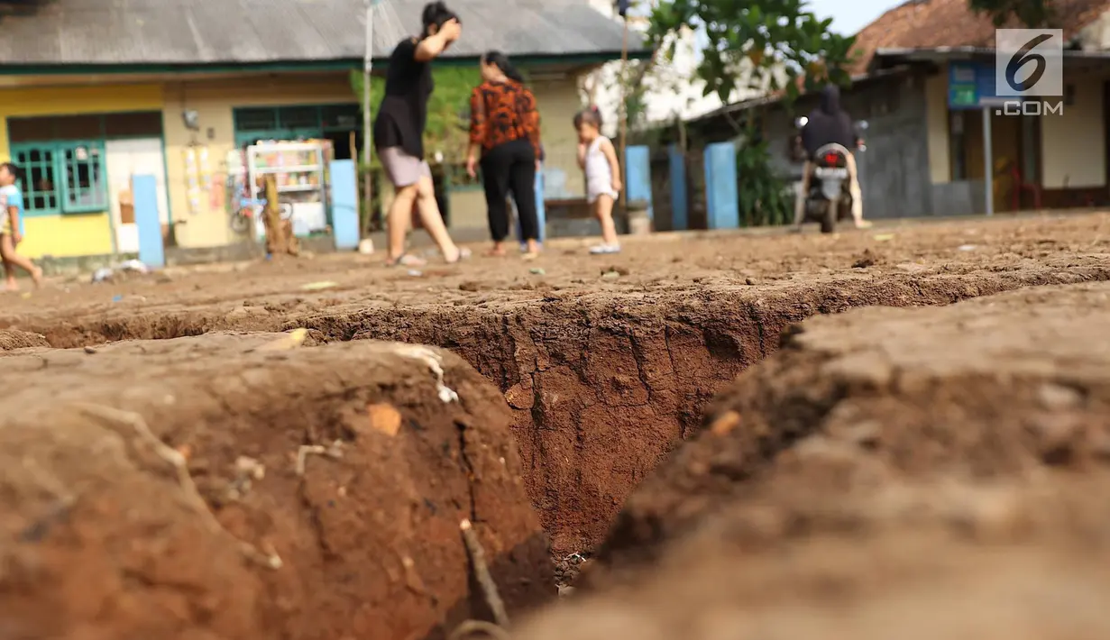 Warga mengamati tanah terbelah di lapangan RT 02 RW 02 Kampung Pedurenan, Kelurahan Cisalak Pasar, Cimanggis, Depok, Jawa Barat, Senin (22/10). Tanah tersebut terbelah sepanjang 20 meter dengan kedalaman 1,5 meter. (Liputan6.com/Immanuel Antonius)