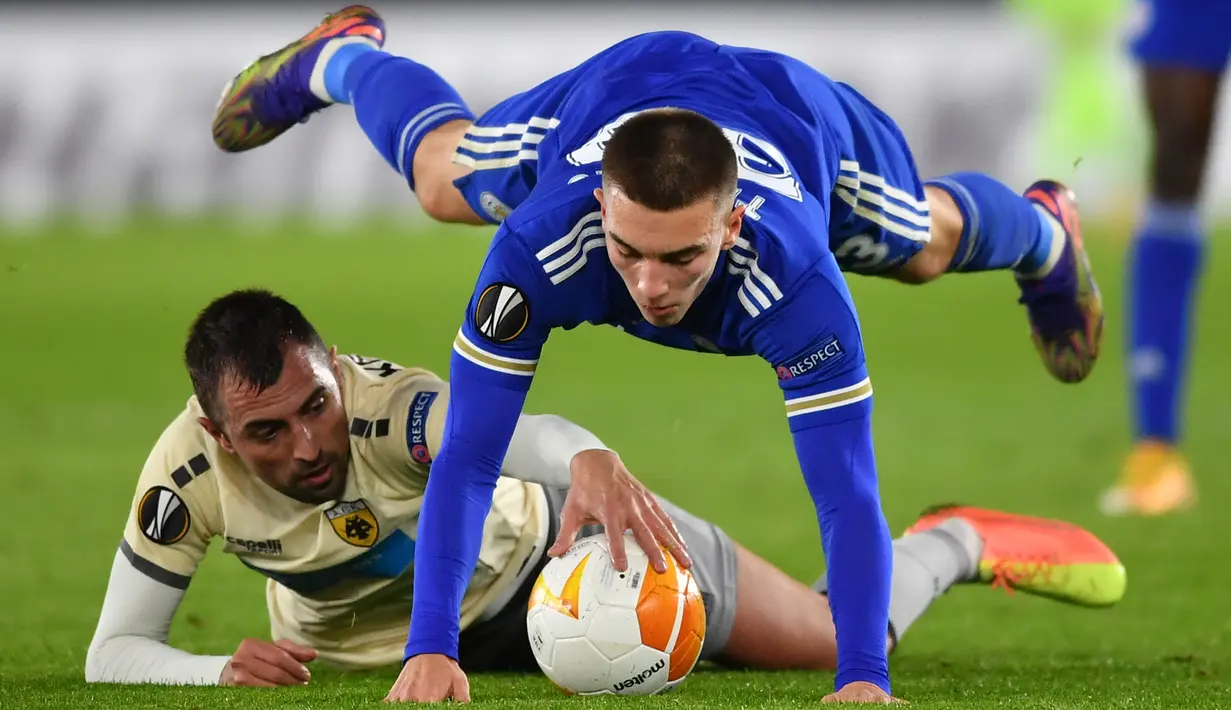 Bek Leicester City Luke Thomas bersaing dengan gelandang AEK Athens, Nenad Krsticic pada matchday Grup G Liga Eropa UEFA di King Power Stadium, Jumat (11/12/2020) dinihari WIB. Leicester City memastikan diri keluar sebagai juara Grup G berkat kemenangan 2-0 atas AEK Athens. (Ben STANSALL/AFP)