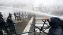 Polisi menyemprotkan air ke arah demonstran saat aksi menolak Reformasi Pensiun di Brussels, Belgia, Selasa (15/11). Mereka menolak rencana pemerintah yang akan menaikkan usia pensiun dari 56 menjadi 63 tahun. (REUTERS / Yves Herman)