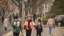 <p>Orang-orang yang memakai masker berjalan di sepanjang jalan pada siang hari dengan kualitas udara yang buruk di Beijing, Jumat, 10 Maret 2023. Ibu kota ini dulu juga terkenal dengan debu musim semi dan badai pasir yang disebabkan oleh angin yang bertiup dari perbukitan loess di sepanjang bagian atas Sungai Kuning ke arah barat. (AP Photo/Mark Schiefelbein)</p>