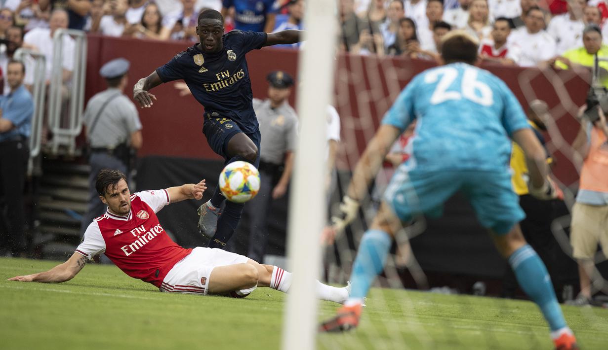 Bek Real Madrid, Ferland Mendy  berusaha melewati bek Arsenal, Carl Jenkinson  selama pertandingan International Champions Cup (ICC) 2019 di FedExField, Landover, Maryland (24/7/2019). Madrid menang adu penalti atas Arsenal 3-2 (2-2). (AFP Photo/Jim Watson)