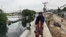Warga melintas di atas tanggul pantai di Kamal Muara, Jakarta, Rabu (26/12). Pembangunan tanggul pantai di Kamal Muara dengan panjang 740 meter yang akan rampung pada 2020. (Liputan6.com/Herman Zakharia)