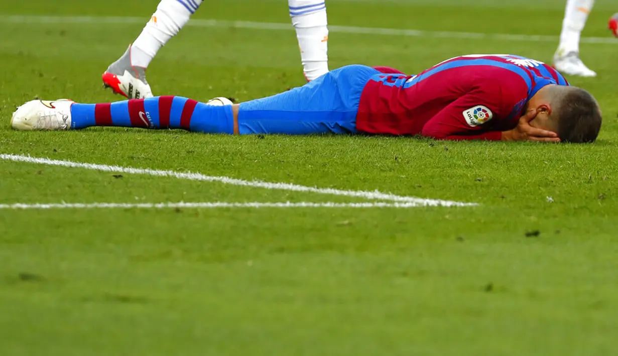 Pemain Barcelona Gerard Pique berbaring di lapangan saat melawan Real Madrid pada pertandingan La Liga Spanyol di Stadion Camp Nou, Barcelona, Spanyol, Minggu (24/10/2021). Real Madrid menang 2-1. (AP Photo/Joan Monfort)