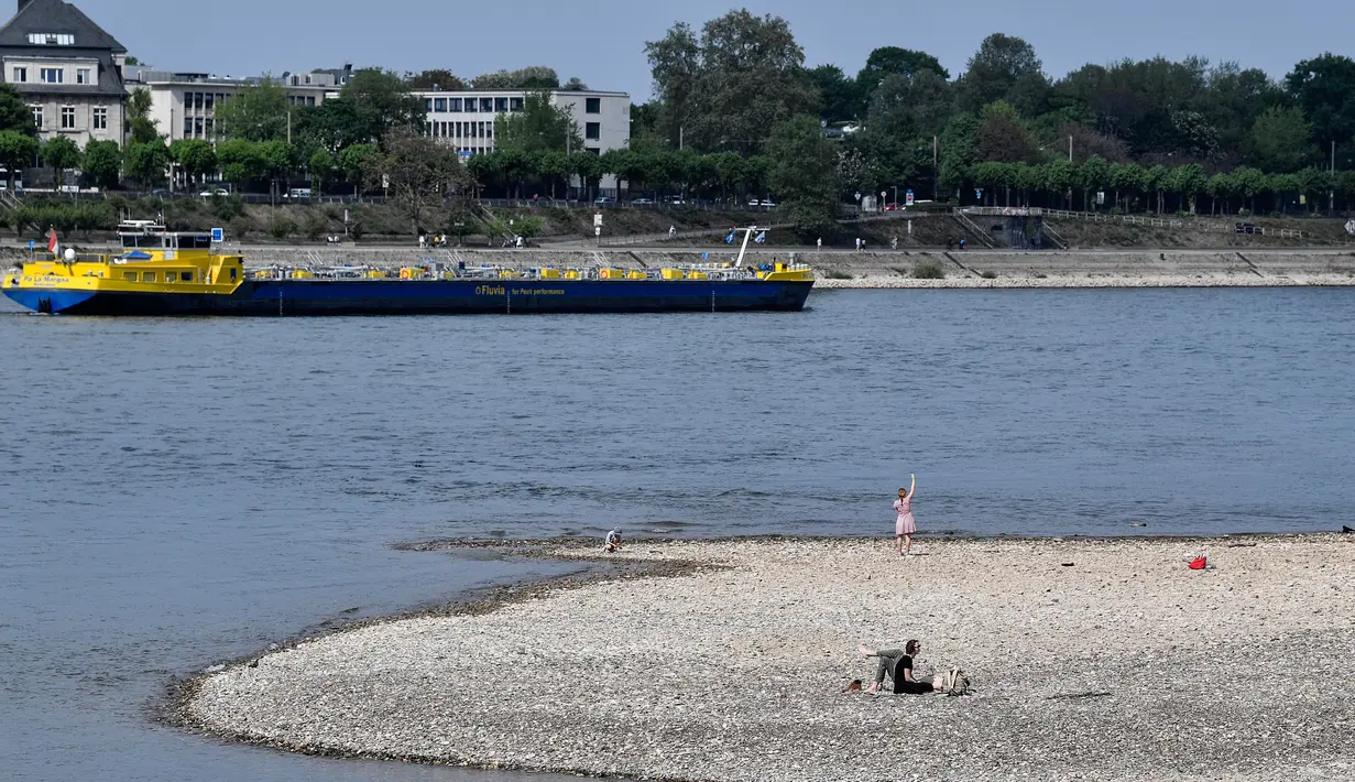 Orang-orang menikmati cuaca cerah di tepi sungai Rhine yang mengering akibat kemarau panjang di Cologne, Jerman pada 27 April 2020. April tahun ini adalah salah satu bulan terkering dan berimbas kepada petani dan industri. (AP/Martin Meissner)