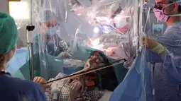 Musisi Dagmar Turner bermain biola saat operasi pengangkatan tumor otak di King's College Hospital, London, 31 Januari 2020. Turner terus memainkan biola saat pengangkatan tumor dari lobus frontal bagian kanan, dekat dengan bagian yang mengontrol gerakan tangan kirinya (KING'S COLLEGE HOSPITAL/AFP)