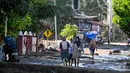 Sebelumnya, curah hujan ekstrem sejak Kamis (27/11) malam hingga Jumat (28/11/2025) dini hari memicu bencana hidrometeorologi di 14 kecamatan di Pidie Jaya. Tampak dalam foto, orang-orang berjalan di jalan yang tertutup lumpur setelah banjir bandang di Meureudu, Kabupaten Pidie Jaya, Provinsi Aceh, pada 29 November 2025. (CHAIDEER MAHYUDDIN/AFP)