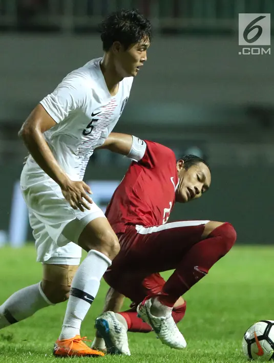 Bek timnas Indonesia U-23, Hansamu Yama Pranata (bawah) mencoba melewati pemain Korea Selatan U-23, Kim Jeung Ho pada laga persahabatan di Stadion Pakansari, Kab Bogor, Sabtu (23/6). Indonesia U-23 kalah 1-2. (Liputan6.com/Helmi Fithriansyah)