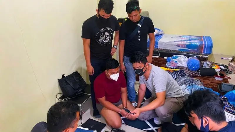 Pria yang menyamar menjadi wanita (masker putih) saat ditangkap Polda Riau karena mengancam menyebar video call sex.