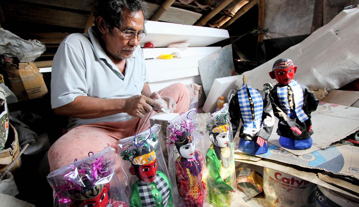 Seorang perajin menyelesaikan pembuatan miniatur ondel-ondel di kawasan Kramat Pulo, Jakarta, Rabu (18/6/14). (Liputan6.com/Faizal Fanani)