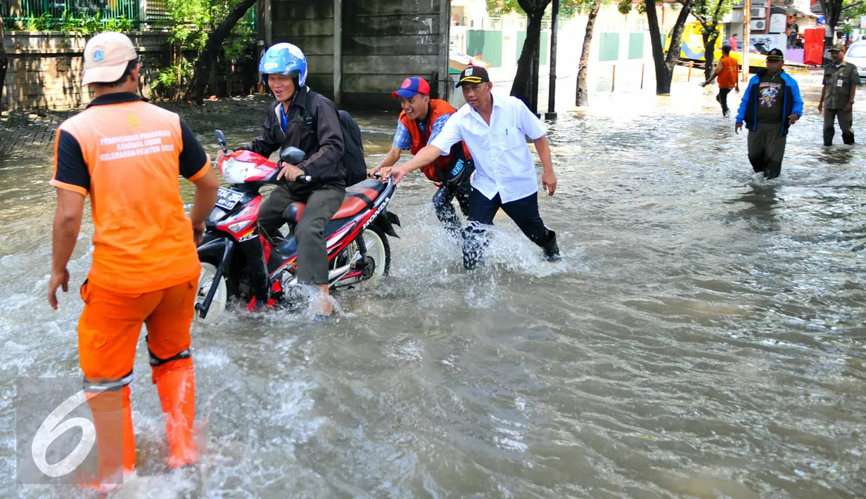 Petugas PPSU membantu pengedara motor untuk melintasi banjir yang terjadi di Jalan Pejaten Raya, Jakarta Selatan, Kamis (21/4/2016). Akibat banjir, kemacetan terjadi cukup panjang di Jalan Pejaten Raya. (Liputan6.com/Yoppy Renato)
