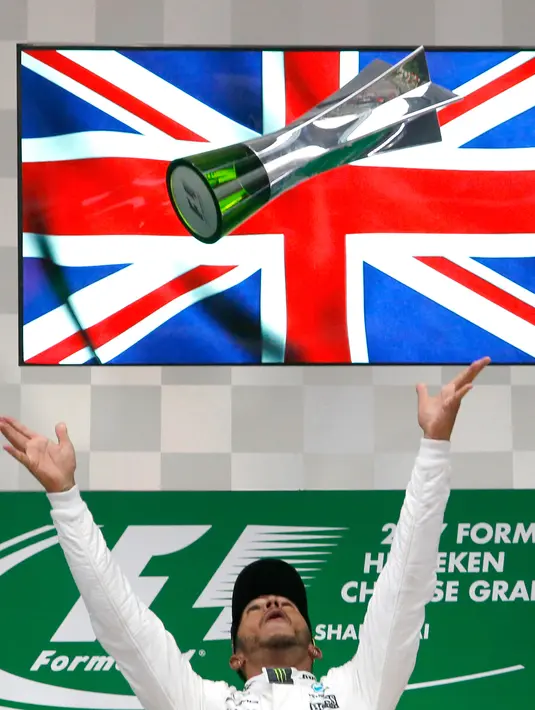 Pembalap Mercedes, Lewis Hamilton melemparkan trofinya di atas podium setelah memenangi GP China di Sirkuit Internasional Shanghai, Minggu (9/4). Kemenangan Hamilton ini membuatnya sudah lima kali memenangi GP China. (AP Photo/Toru Takahashi)
