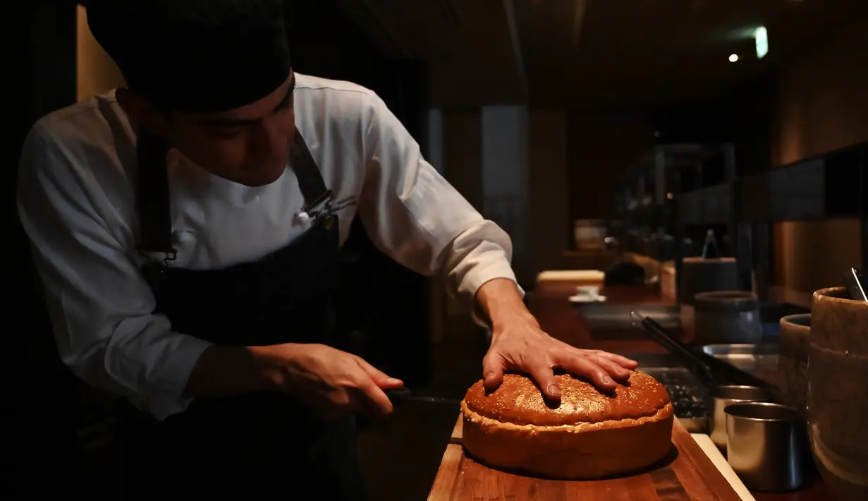 Chef dari restoran The Oak Door, Patrick Shimada menyiapkan burger raksasa di hotel Grand Hyatt Tokyo, Senin (1/4). Restoran itu membuat hamburger wagyu seukuran bola sepak yang disajikan dengan roti bertabur emas untuk merayakan penobatan kaisar baru Jepang bulan depan. (CHARLY TRIBALLEAU/AFP)