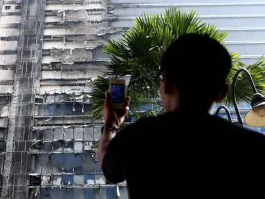 Seorang penghuni apartemen mengambil gambar Gedung Neo Soho pasca kebakaran di Tanjung Duren, Jakarta, Kamis (10/11). Kebakaran Gedung yang masih dalam tahap pembangunan itu terjadi Rabu (9/11) sekitar pukul 20.30. (Liputan6.com/Gempur M. Surya)