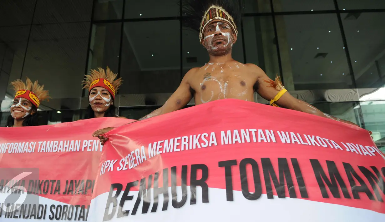 Sejumlah pemuda Papua mengenakan pakaian adat membentangkan spanduk di depan Gedung KPK, Jakarta, Senin (19/12). Mereka meminta KPK mengusut kasus korupsi pejabat yang mencalonkan diri pada Pilkada Jayapura 2017. (Liputan6.com/Helmi Affandi)