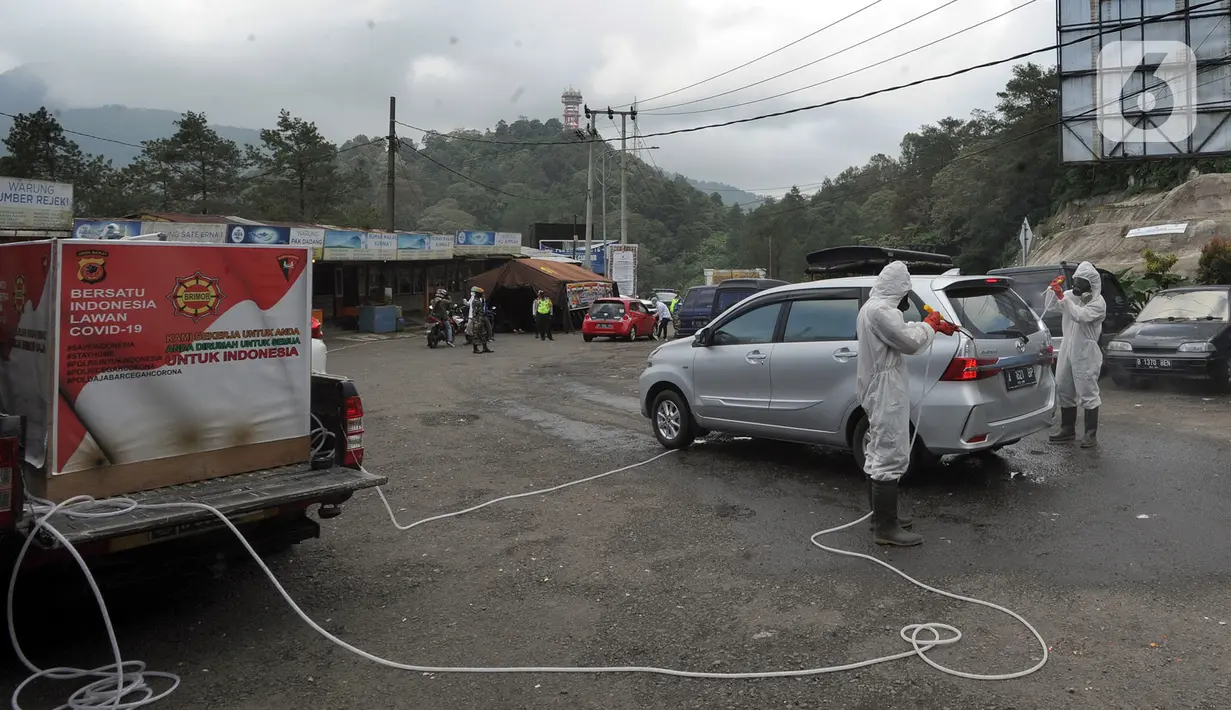 Anggota Batalyon B Brimob Cipanas melakukan penyemprotan disinfektan saat penyekatan arus lalu lintas di kawasan Ciloto, Cianjur, Jawa Barat, Jumat (17/4/2020). Penyemprotan yang dilakukan selama 20 hari tanpa henti ini untuk mencegah penyebaran virus corona COVID-19. (merdeka.com/Arie Basuki)