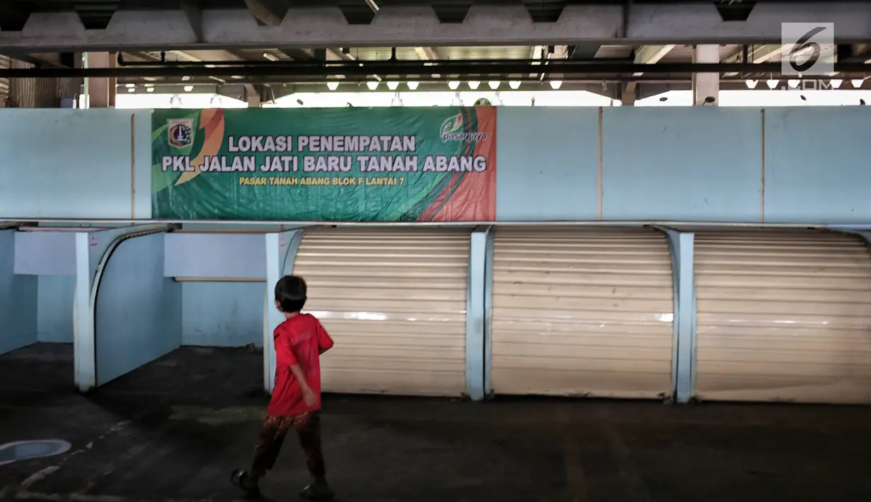 Seorang anak bermain dekat kios penampungan pedagang kaki lima (PKL) yang kosong di Blok F Tanah Abang, Jakarta, Kamis (31/1). Hingga kini tempat untuk PKL yang tidak memperoleh lapak di skybridge Tanah Abang itu tak diminati. (Liputan6.com/Faizal Fanani)