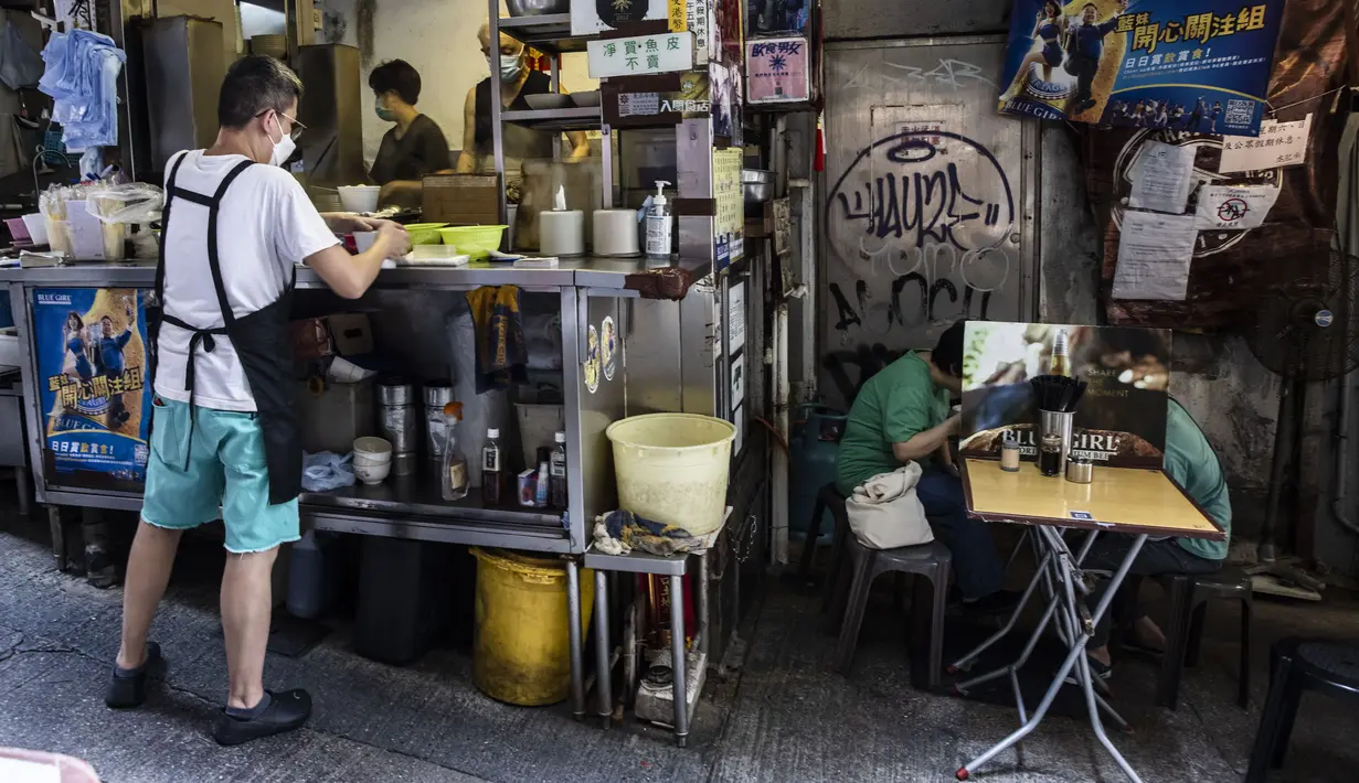 Pelanggan (kanan) bersantap di sebuah restoran saat pemerintah mengumumkan pelonggaran pembatasan Covid-19 paling ketat di Hong Kong, Kamis (14/4/2022). Pelonggaran tersebut memungkinkan salon kecantikan, bioskop, dan pusat kebugaran dibuka kembali mulai 21 April 2022 mendatang. (ISAAC LAWRENCE/AFP)