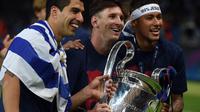 Lionel Messi (tengah) membawa trofi Liga Champions bersama Luis Suarez dan Neymar setelah menang melawan Juventus pada Final di Stadion Olimpiade di Berlin pada Juni 6, 2015. Messi sudah berstatus tanpa klub sejak tanggal 1 Juli 2021 mengingat kontraknya bersama Barcelona usai. (AFP/Patrik Stollarz)