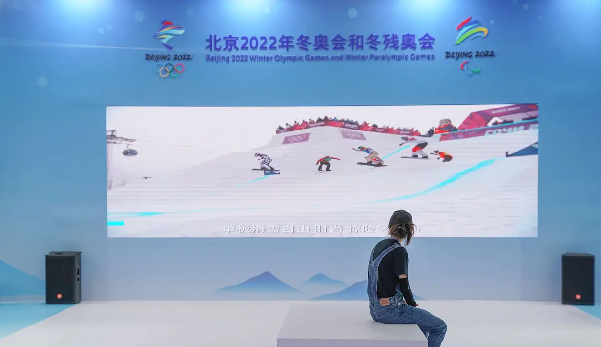 Seorang wanita menonton video promosi olahraga musim dingin di paviliun pameran outdoor di dekat China National Convention Center, lokasi penyelenggaraan Pameran CIFTIS), di Beijing Olympic Park di Beijing, China (1/9/2020).  (Xinhua/Peng Ziyang)