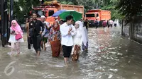 Pengantin Mansur dan Maya melintasi banjir usai melakukan akad nikah di KUA Mampang Prapatan, Jakarta, Selasa (21/2). Walapun banjir sepasang pengantin ini tetap melakukan akad nikah. (Liputan6.com/Herman Zakharia)