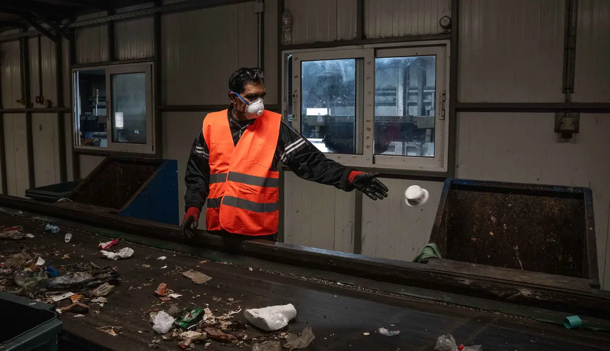 Program pemilahan ini menjadi sangat krusial untuk mengurangi beban tempat pembuangan sampah yang terbatas. Tampak dalam foto, seorang pekerja memisahkan benda-benda plastik dari bahan limbah lainnya di atas conveyor belt di pabrik daur ulang di kota Corfu pada 15 Oktober 2025. (Angelos TZORTZINIS/AFP)