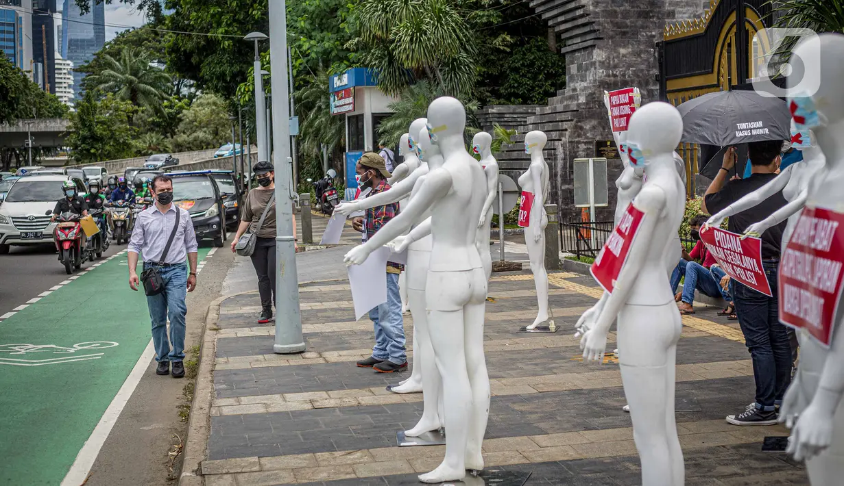 Kendaraan melintas di depan manekin yang dipajang dalam aksi di Polda Metro Jaya, Senin (21/3/2022). Aksi tersebut bentuk dukungan terhadap Haris Azhar dan Fatia Maulidiyanti saat menjalani pemeriksaan terkait kasus dugaan pencemaran nama baik Luhut Binsar Pandjaitan. (Liputan6.com/Faizal Fanani)