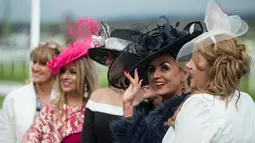 Sejumlah racegoers foto bersama selama menghadiri Festival Grand National di arena Aintree, Liverpool, Inggris, Jumat (7/4). Kehadiran racegoers memberikan nuansa tersendiri di kompetisi pacuan kuda terbesar tersebut. (AFP Photo / Oli Scarff)