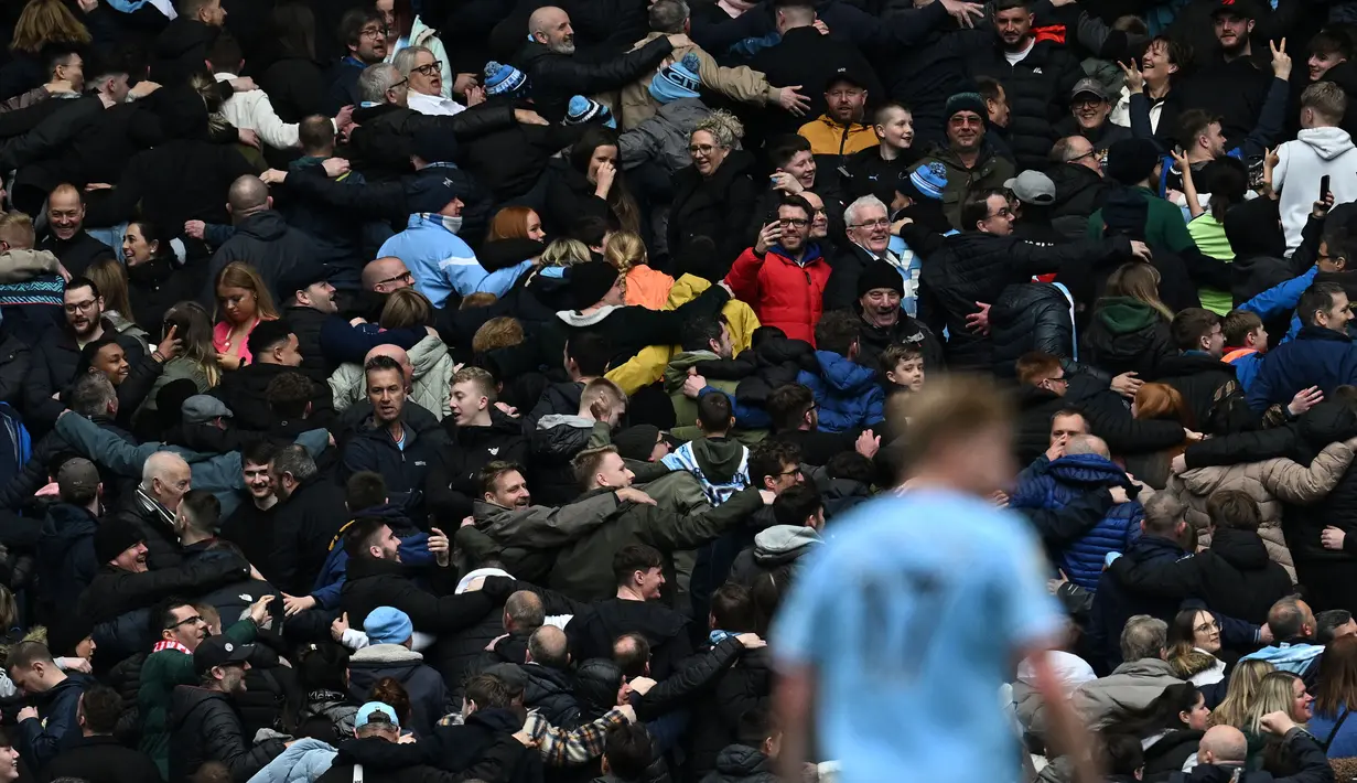 Suporter Manchester City melakukan selebrasi Poznan saat Jack Grealish mencetak gol keempat timnya ke gawang Liverpool pada laga pekan ke-29 Liga Inggris 2022/2023 yang berlangsung di Etihad Stadium, Manchester, Minggu (01/04/2023) WIB. The Cityzens menang dengan skor 4-1. (AFP/Paul Ellis)