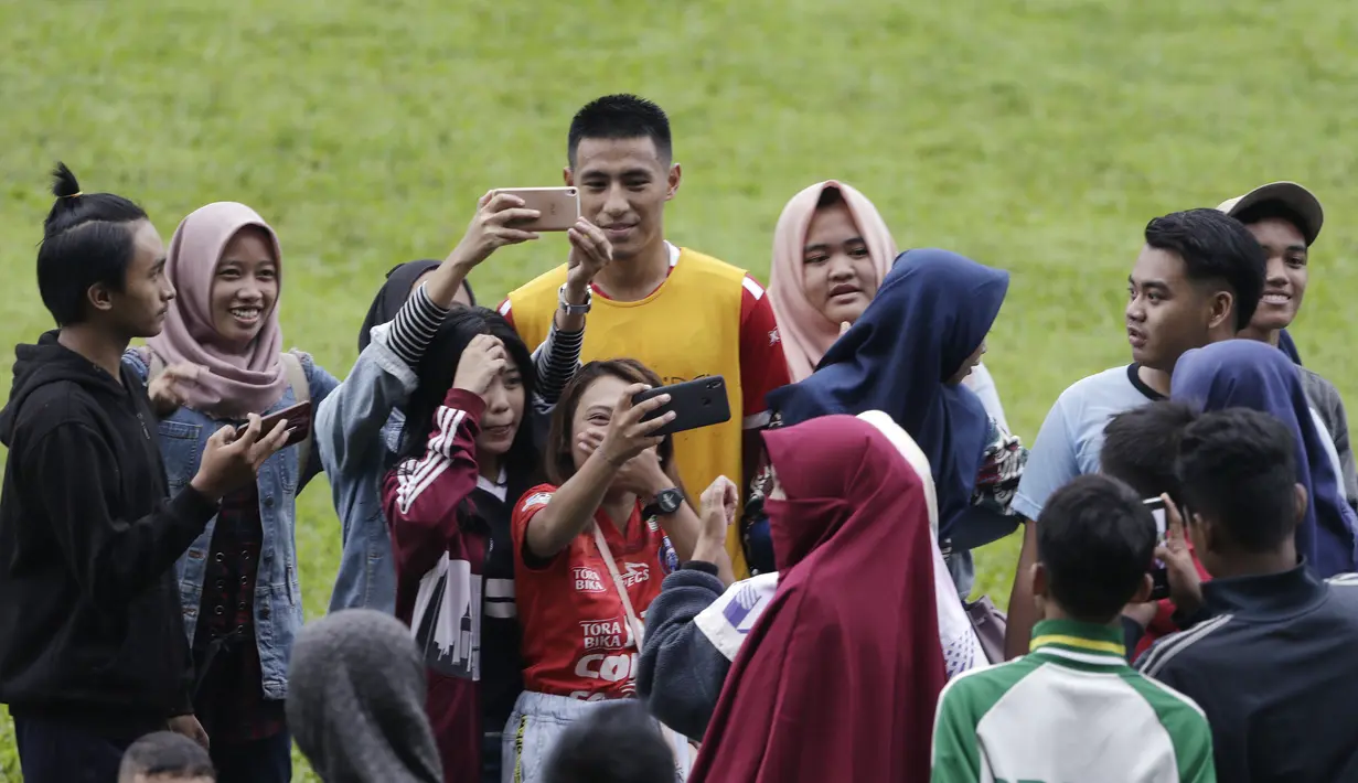 Pemain Arema FC, Hanif Sjahbandi, foto bersama dengan fans usai sesi latihan di Stadion Gajayana, Malang, Kamis (11/4). Setelah sesi latihan, pemain Arema FC melayani permintaan fans untuk foto bersama. (Bola.com/Yoppy Renato)