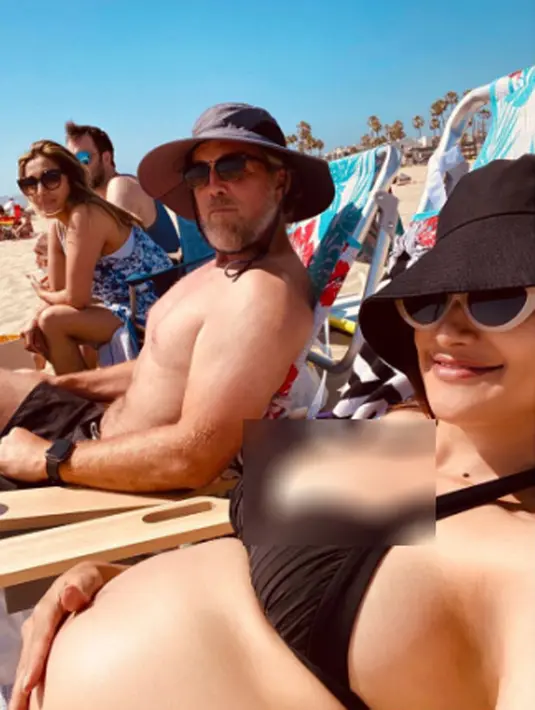 Rahma membagikan potret perutnya yang besar di pinggir pantaii Los Angeles. Rahma mengenakan bikini, topi dan kaca mata hitam tersenyum menghadap kamera. Sang suami tercinta tampak mendampinginya. (Instagram/raazharita)