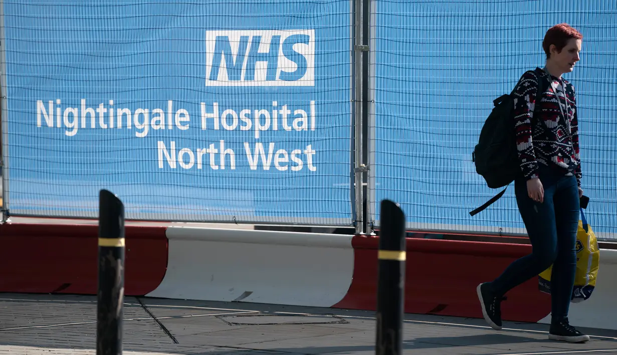 Pejalan kaki melewati papan penanda di pusat konferensi Manchester Central yang menjadi rumah sakit lapangan bernama NHS Nightingale Hospital North West untuk membantu memerangi COVID-19 di Manchester, 13 April 2020.. Rumah sakit itu dapat menampung hingga 750 pasien. (Xinhua/Jon Super)