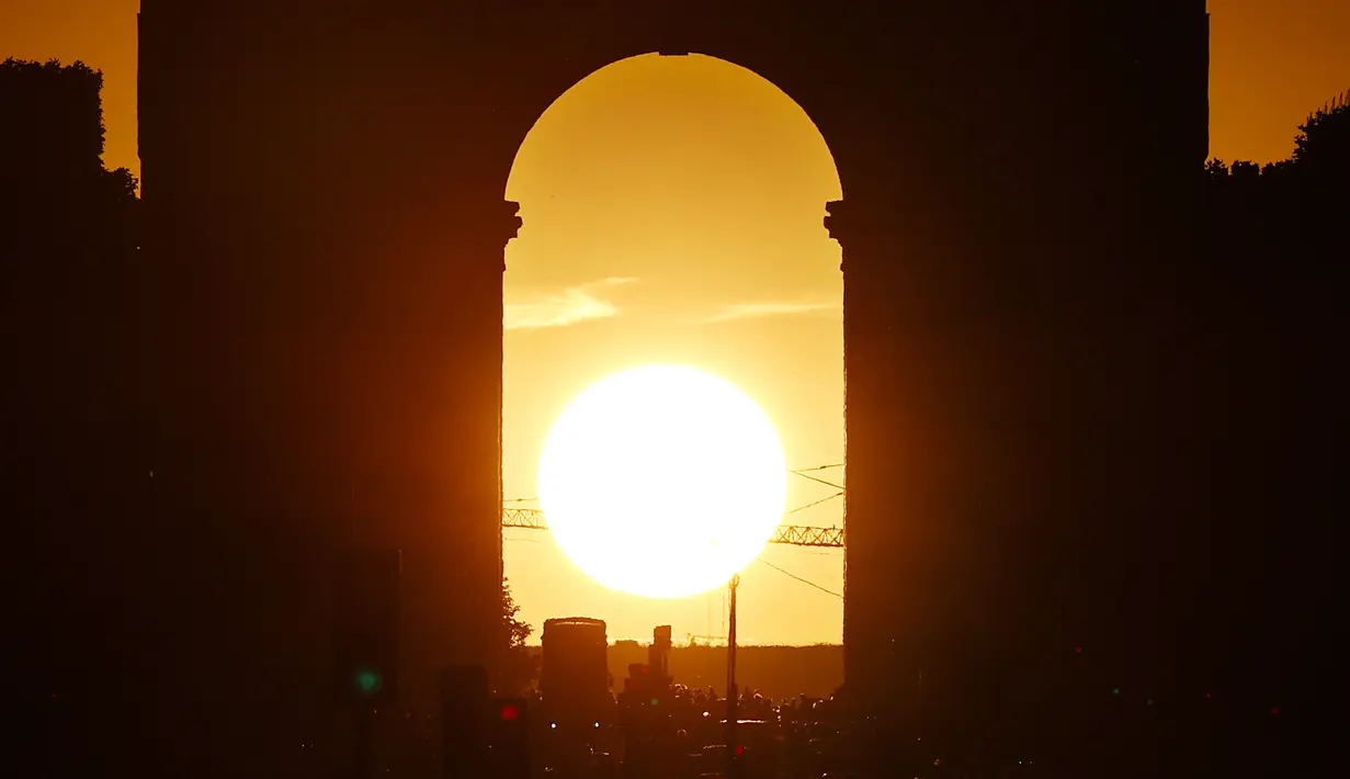 Foto yang diambil pada 2 Agustus 2022 menunjukkan Arc de Triomphe saat matahari terbenam, di Paris. Peristiwa yang dikenal sebagai "Paris Henge" ini terjadi dua kali setahun. (Photo by Stefano RELLANDINI / AFP)