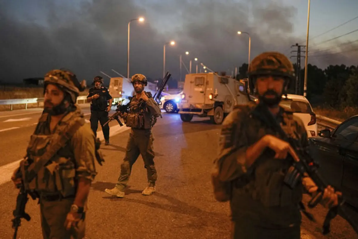 Tentara Israel memblokir jalan dengan latar belakang asap kebakaran setelah roket bombardir Hizbullah Lebanon menghantam Dataran Tinggi Golan yang dianeksasi Israel, Selasa, 9 Juli 2024. (AP)