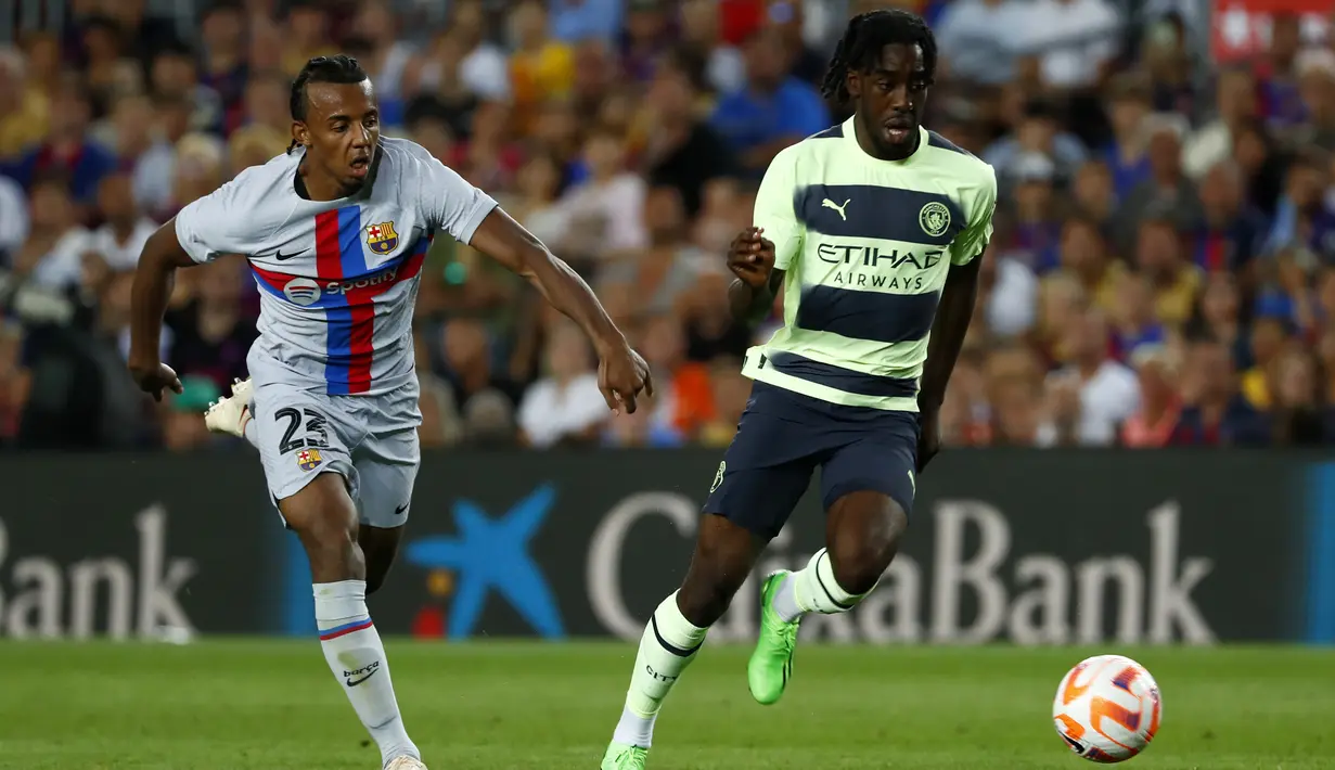 Bek Manchester City Joshua Wilson berlari dengan bola melewati bek Barcelona Jules Kounde pada sebuah laga amal di Stadion Camp Nou, Kamis (25/8/2022) dini hari WIB. Laga Barcelona vs Man City berjalan ketat, skor akhir sama kuat 3-3. (AP Photo/Joan Monfort)