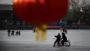 Sepasang warga menggunakan ponsel untuk berswafoto saat menaiki kereta luncur di danau beku di Beijing pada Selasa (12/1/2021). Ketika musim dingin tiba, danau di Beijing banyak yang membeku dan dijadikan area ice skating musiman. (Photo by WANG Zhao / AFP)